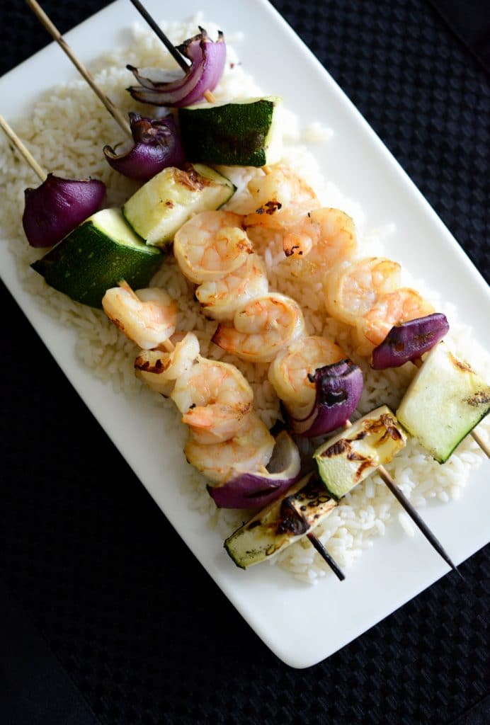 Dijon Mustard Grilled Shrimp Skewers over rice on a white plate. 