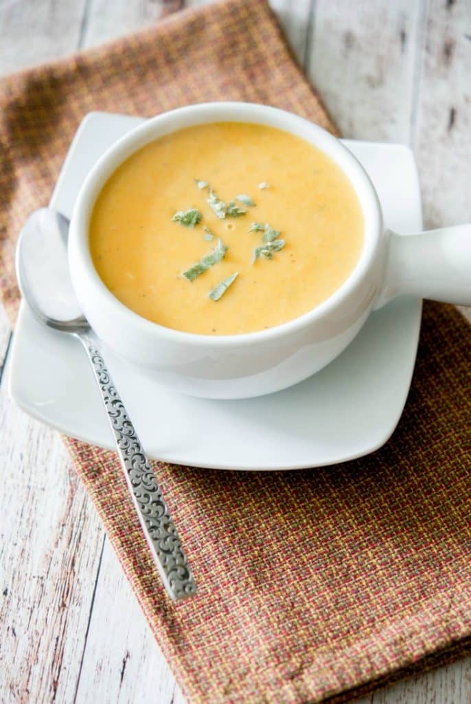 Sweet Potato and Cannellini Bean Soup in a white soup crock with spoon.