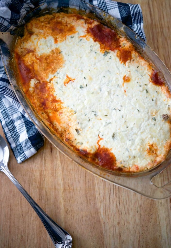 Beef Ricotta Casserole in a glass dish on a wooden cutting board. 