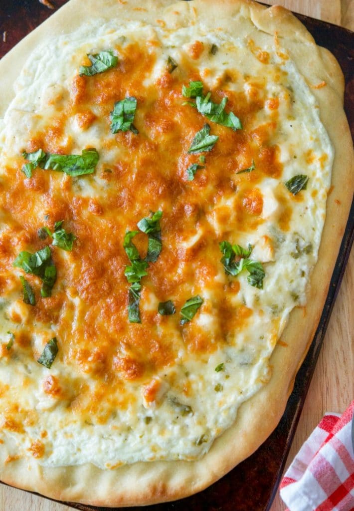 Lemon Chicken Ricotta Pizza on a wooden cutting board overhead.