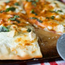 A close up of Lemon Chicken Ricotta Pizza on a pizza stone.