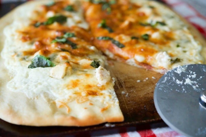 A close up of Lemon Chicken Ricotta Pizza on a pizza stone.