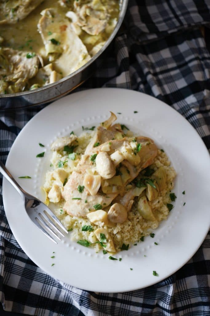 Artichoke Chicken over rice on a plate with a fork. 