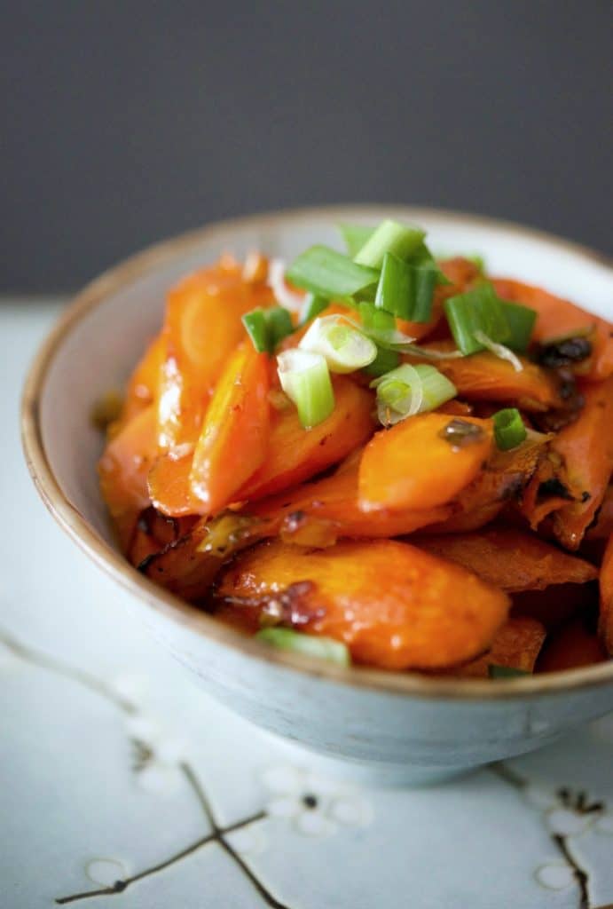 A close up of Sweet and Sour Roasted Carrots in a bowl. 