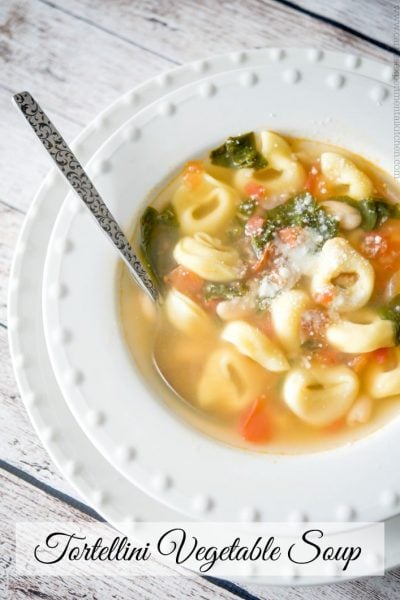 A bowl of soup and a spoon, with Tortellini