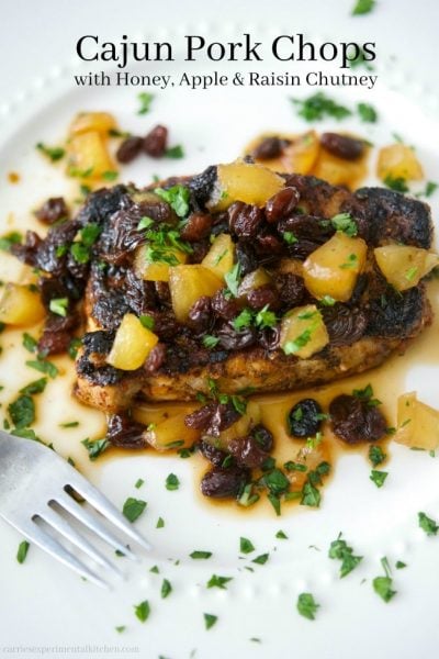 A pork chop with chutney on a white plate.