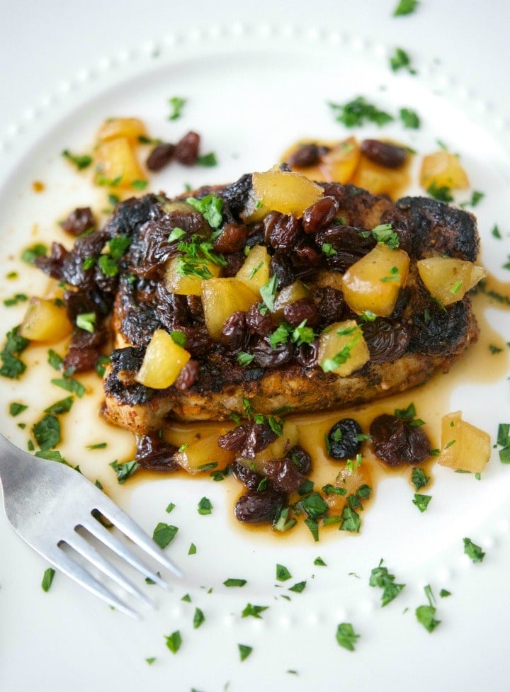 Boneless pork chop on a plate with apple raisin chutney.