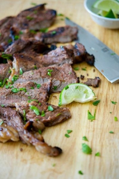 Rib eye steak sliced on a wooden cutting board.