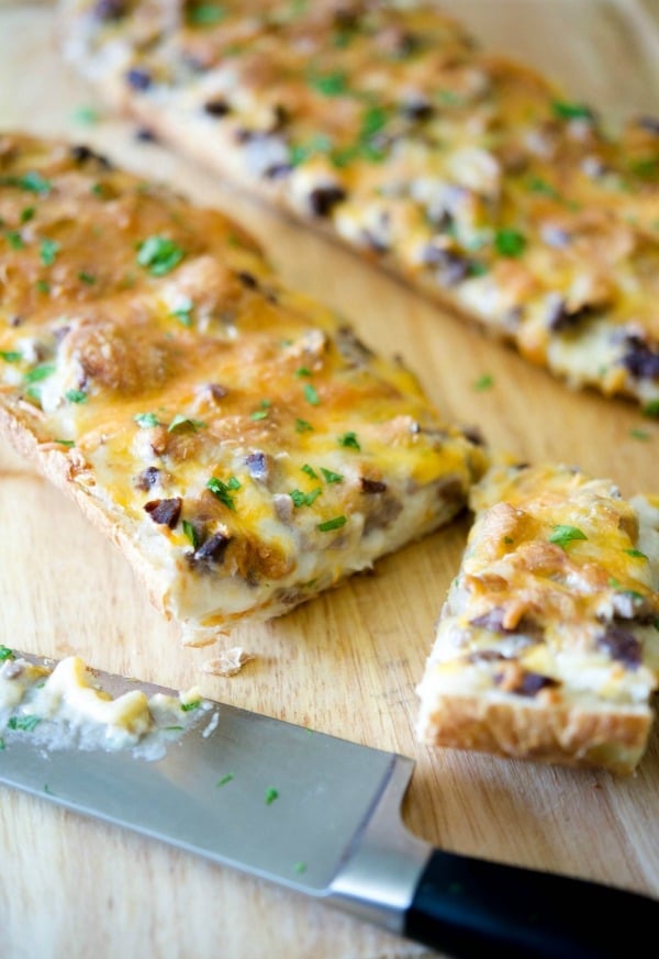 A slice of pizza sitting on top of a wooden cutting board, Steak & Cheddar French Bread Pizza