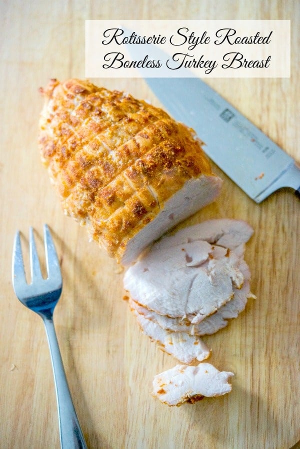 Boneless turkey breast seasoned with rotisserie seasonings sliced on a wooden cutting board. 
