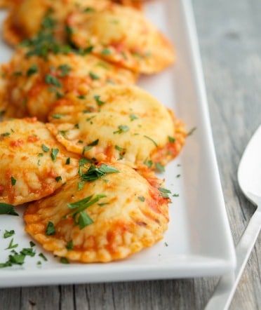 Neapolitan Ravioli with sauce on a white rectangle plate. 