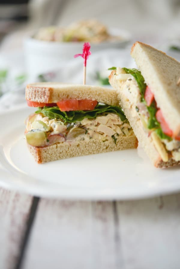 A sandwich cut in half on a plate, with Chicken and Salad