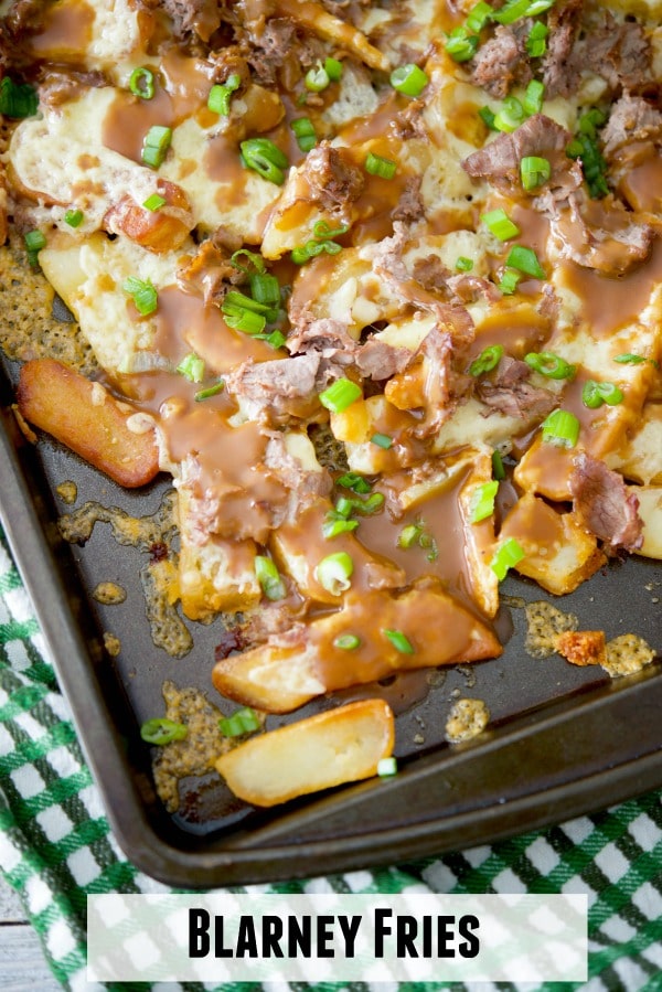 French fries on a sheet pan topped with gravy and roast beef. 