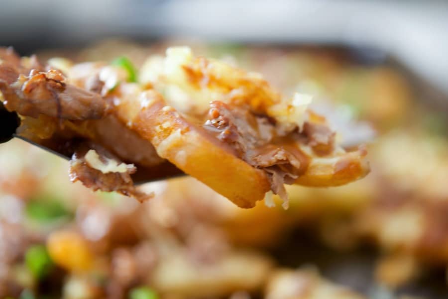 A close up steak fries topped with gravy, cheese and roast beef. 