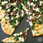 Spinach, Goat Cheese & Kalamata Olive Flatbread whole with a slice cut out