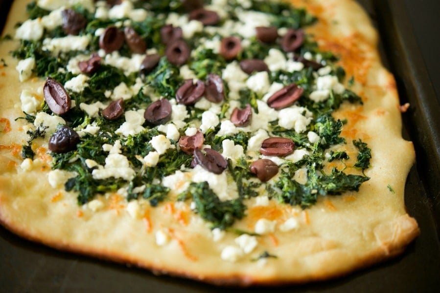 a close up of Spinach, Goat Cheese & Kalamata Olive Flatbread on a plate