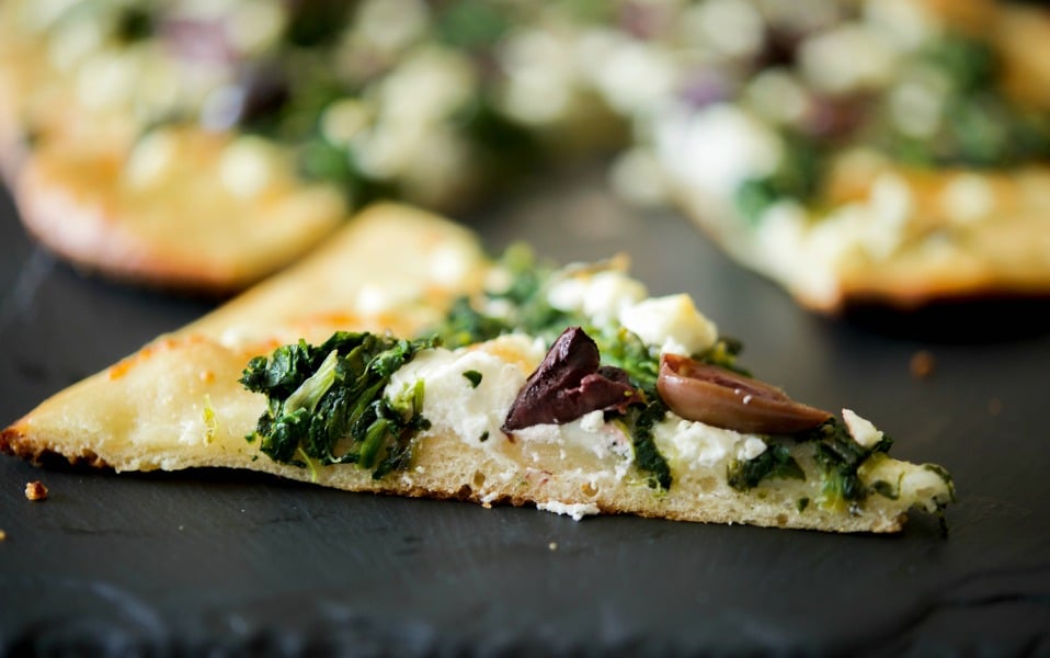 a slice of Spinach, Goat Cheese & Kalamata Olive Flatbread