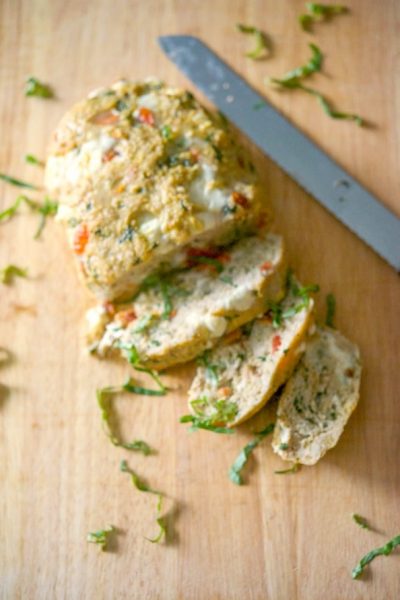 Caprese Chicken Meatloaf sliced on a wooden cutting board.