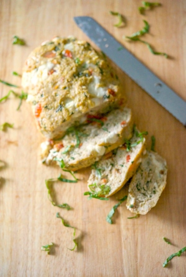 Caprese Chicken Meatloaf sliced on a wooden cutting board. 