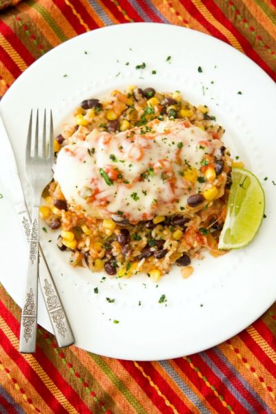 Tex Mex Chicken and Rice made with black beans, corn, salsa and boneless chicken breasts on a white plate.