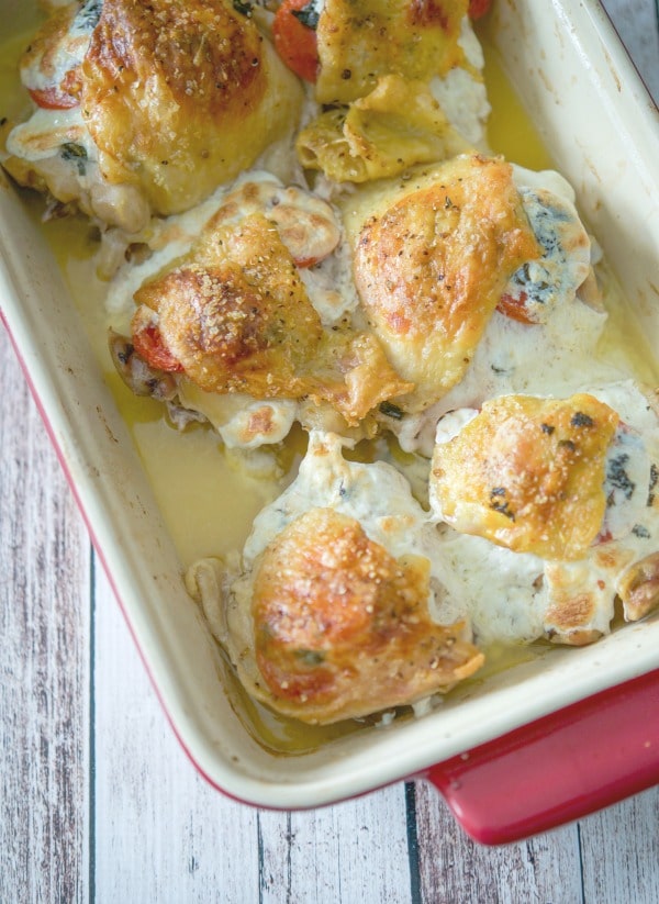 Caprese Stuffed Chicken Thighs in red baking dish. 