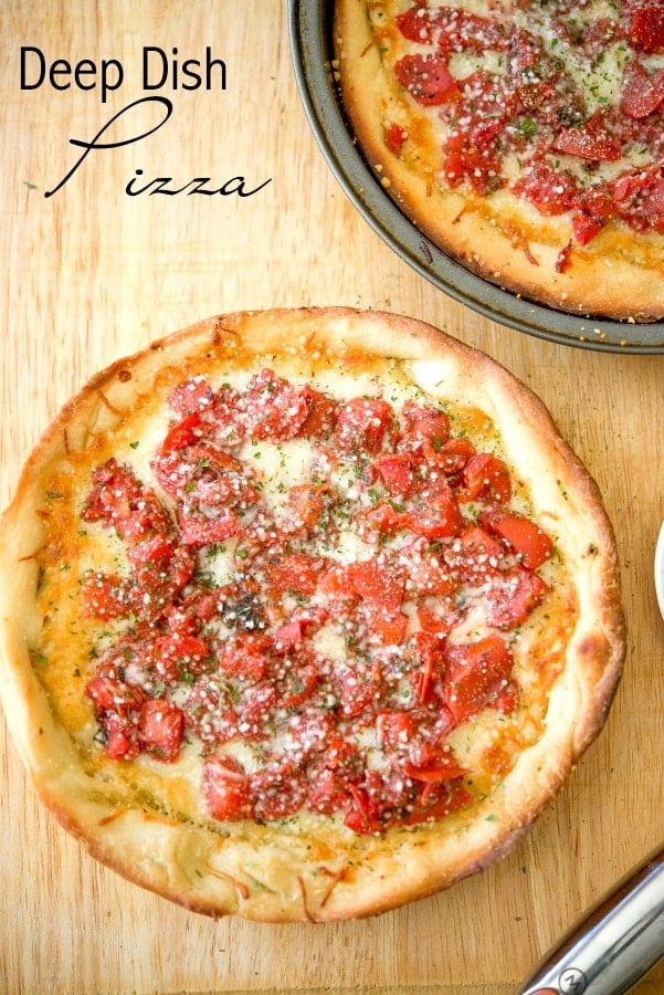 A deep dish pizza sitting on top of a wooden cutting board, with Cheese and Tomato