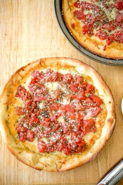 A deep dish pizza sitting on top of a wooden cutting board.