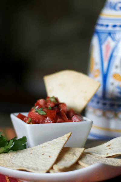 A close up of Homemade Tortilla Chips dipped into pico de gallo.