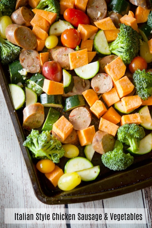 Sliced chicken sausage and vegetables on a sheet pan before cooked. 