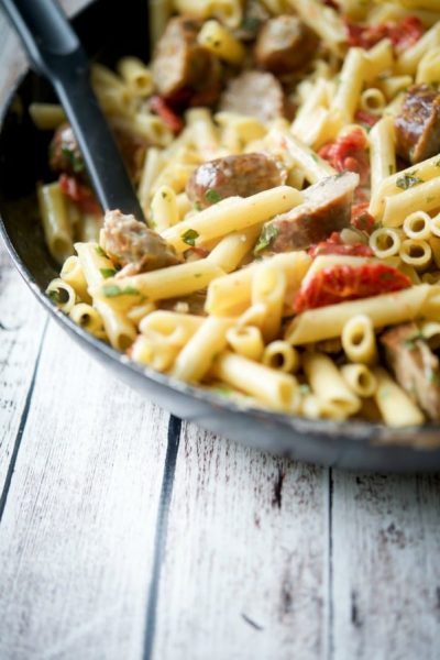 A close up of Pasta with Sun Dried Tomato Basil Cream Sauce in a skillet with a spoon.