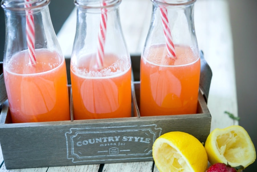 Strawberry Lemonade in a wooden crate with a lemon. 