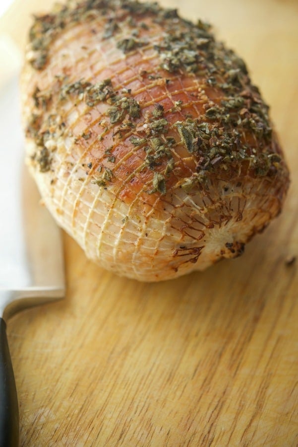 Garlic and Sage Roasted Boneless Turkey Breast on a wooden cutting board. 
