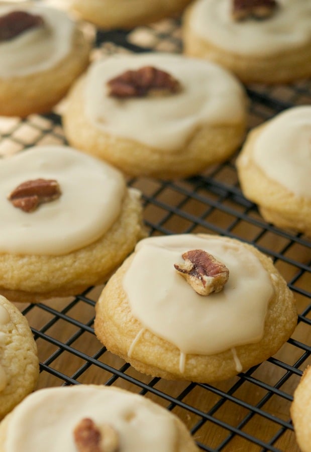 Maple Sugar Cookies coated with a maple syrup glaze and pecans on a cooling rack. 