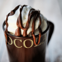 a close up of a brown mug with whipped cream and drizzled nutella