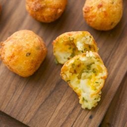 Food on a wooden cutting board, with Mashed potato puffs