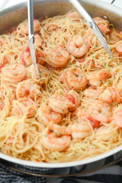 A bowl of cajun shrimp and pasta with tongs