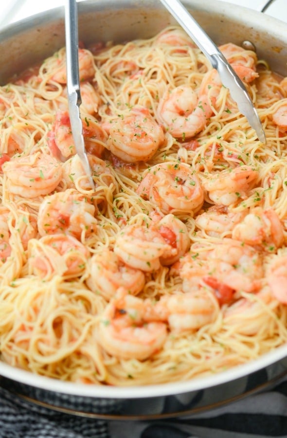 A bowl of cajun shrimp and pasta with tongs