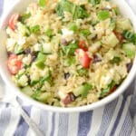 Greek Orzo Salad made with Orzo pasta, Kalamata olives, cucumbers, tomatoes, spinach and Feta cheese in a light lemon, oregano vinaigrette.