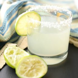 A glass of margarita with a lime