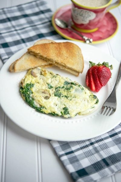 A plate of Spinach, mushroom and havarti egg white omlet with a fork