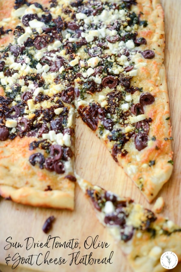 A close up of sun-dried tomato, olive and goat cheese flat bread