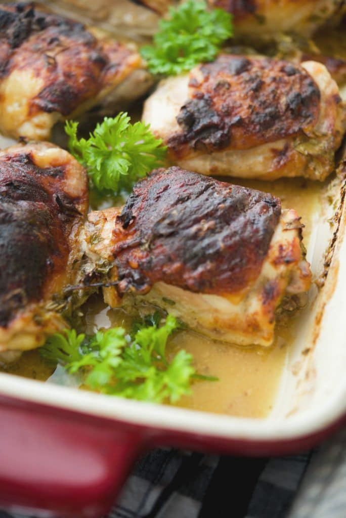 A close up of chicken thighs baked in a marinade of apple cider and Dijon mustard.