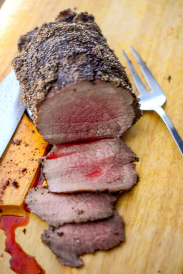 Espresso Encrusted Roast Beef sliced on a wooden cutting board. 