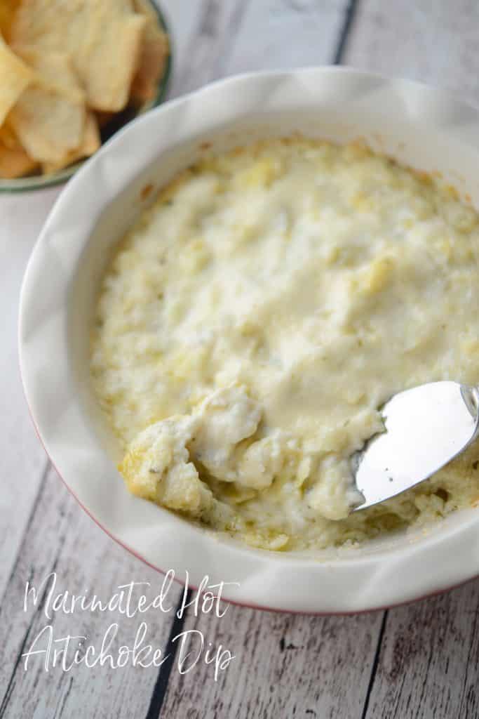 A close up of Marinated Hot Artichoke Dip with a knife