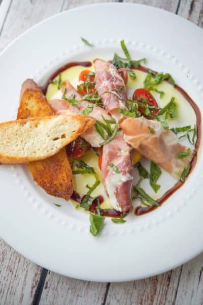 A plate of food on a table, with Mozzarella and Prosciutto