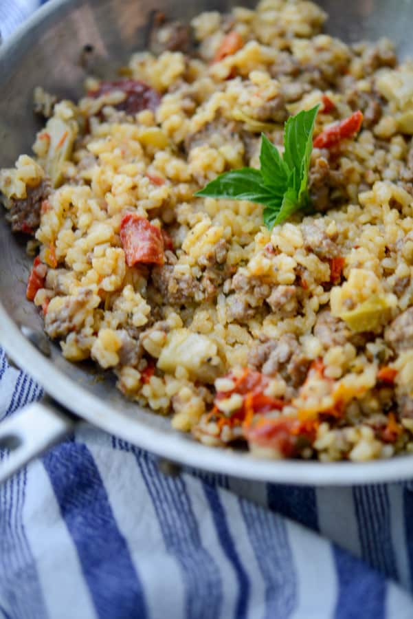 This risotto made with Italian sausage, artichoke hearts and sun dried tomatoes is deliciously flavorful and can be made in one skillet.