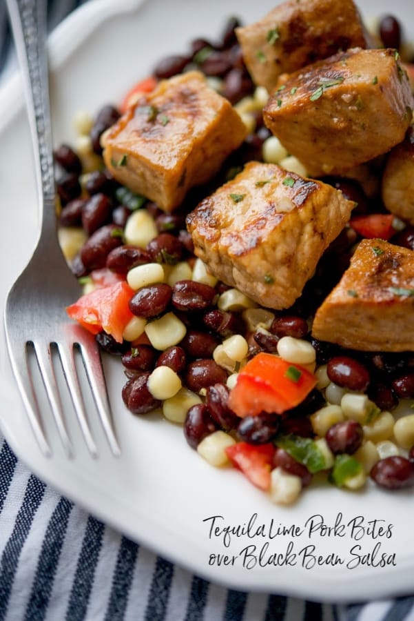 A close up of Tequila Lime Pork Bites over Black Bean Salsa