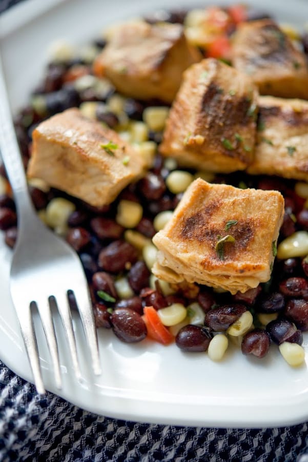 A plate of Tequila Lime Pork Bites over Black Bean Salsa with a fork