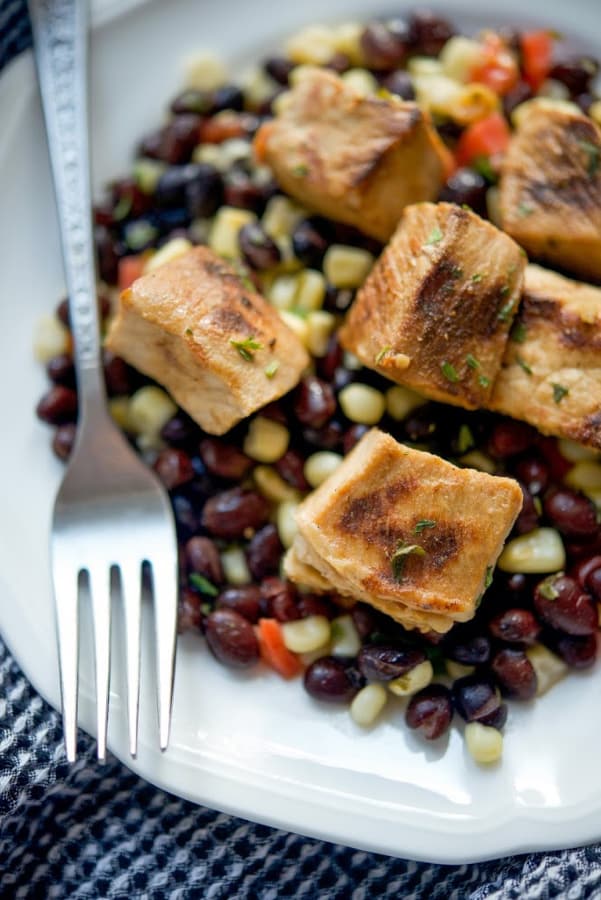 A plate of Tequila Lime Pork Bites over Black Bean Salsa on a plate 