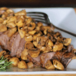 sauteed mushrooms on a steak on a plate